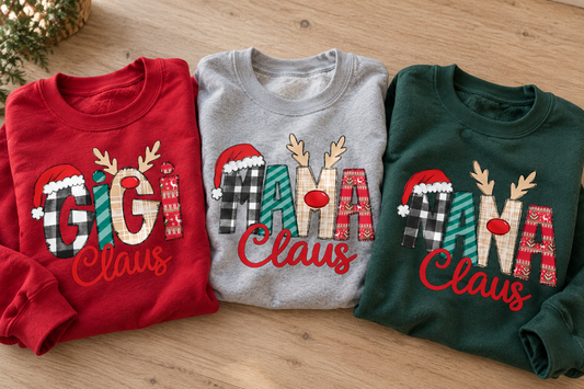 Close-up of folded red, grey and green personalized Claus sweatshirts with festive GiGi, MAMA and NANA designs.