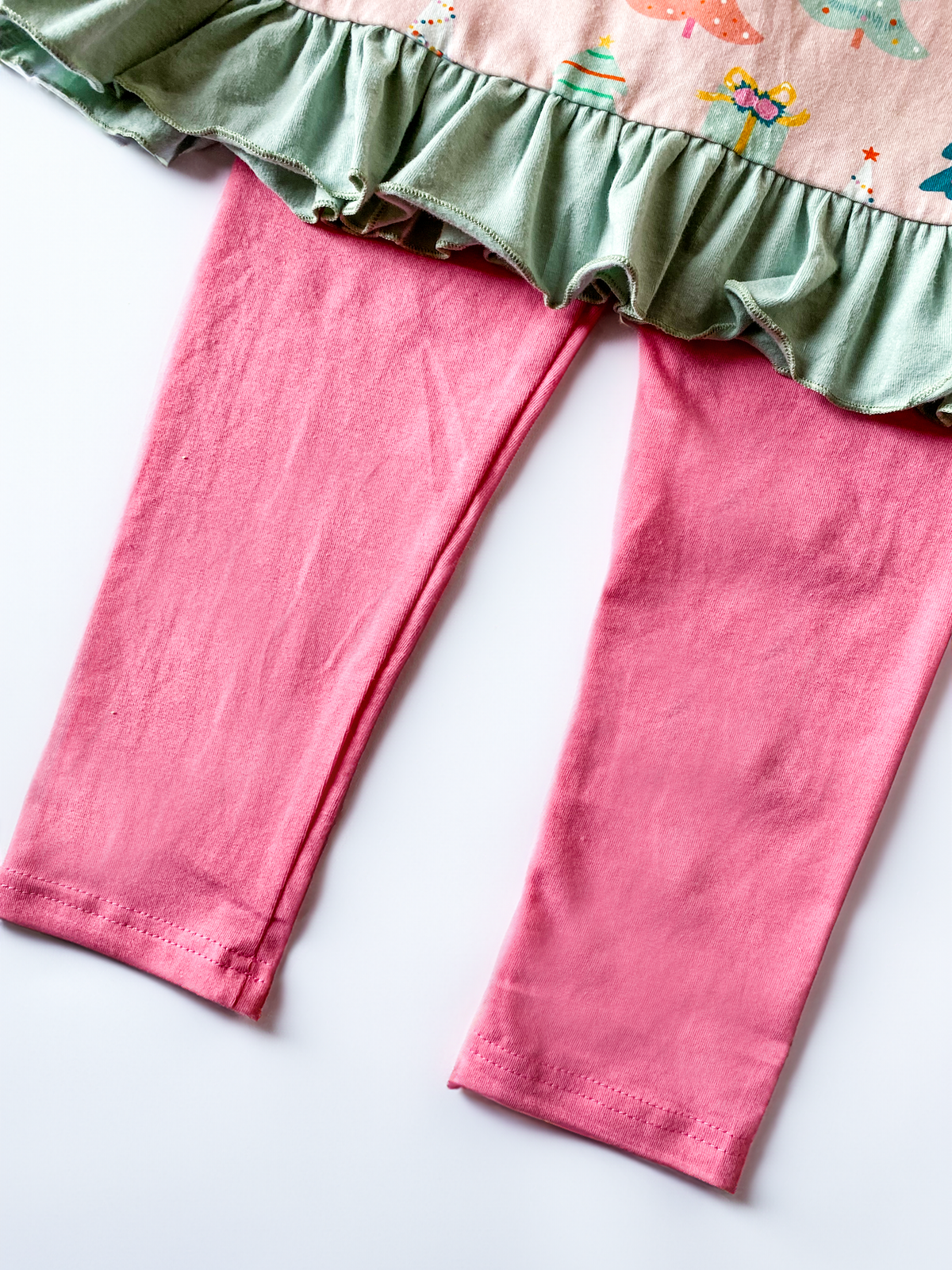 Close-up of green ruffle trim and pink leggings on girls Christmas outfit