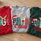 Close-up of folded red, grey and green personalized Claus sweatshirts with festive GiGi, MAMA and NANA designs.