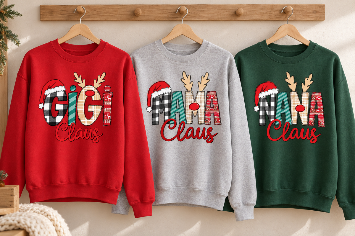 Red GiGi Claus, grey MAMA Claus and green NANA Claus adult Christmas sweatshirts hanging from a wooden rack.