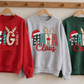 Hanging red, grey and green Claus sweatshirts showing festive GiGi, MAMA and NANA lettering with Santa hats and reindeer antlers.