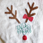 Close-up of embroidered reindeer design with antlers, red bow, monogram, and red pom-pom nose.