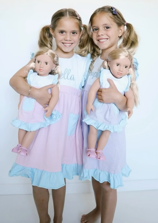 Girls holding dolls wearing matching dresses