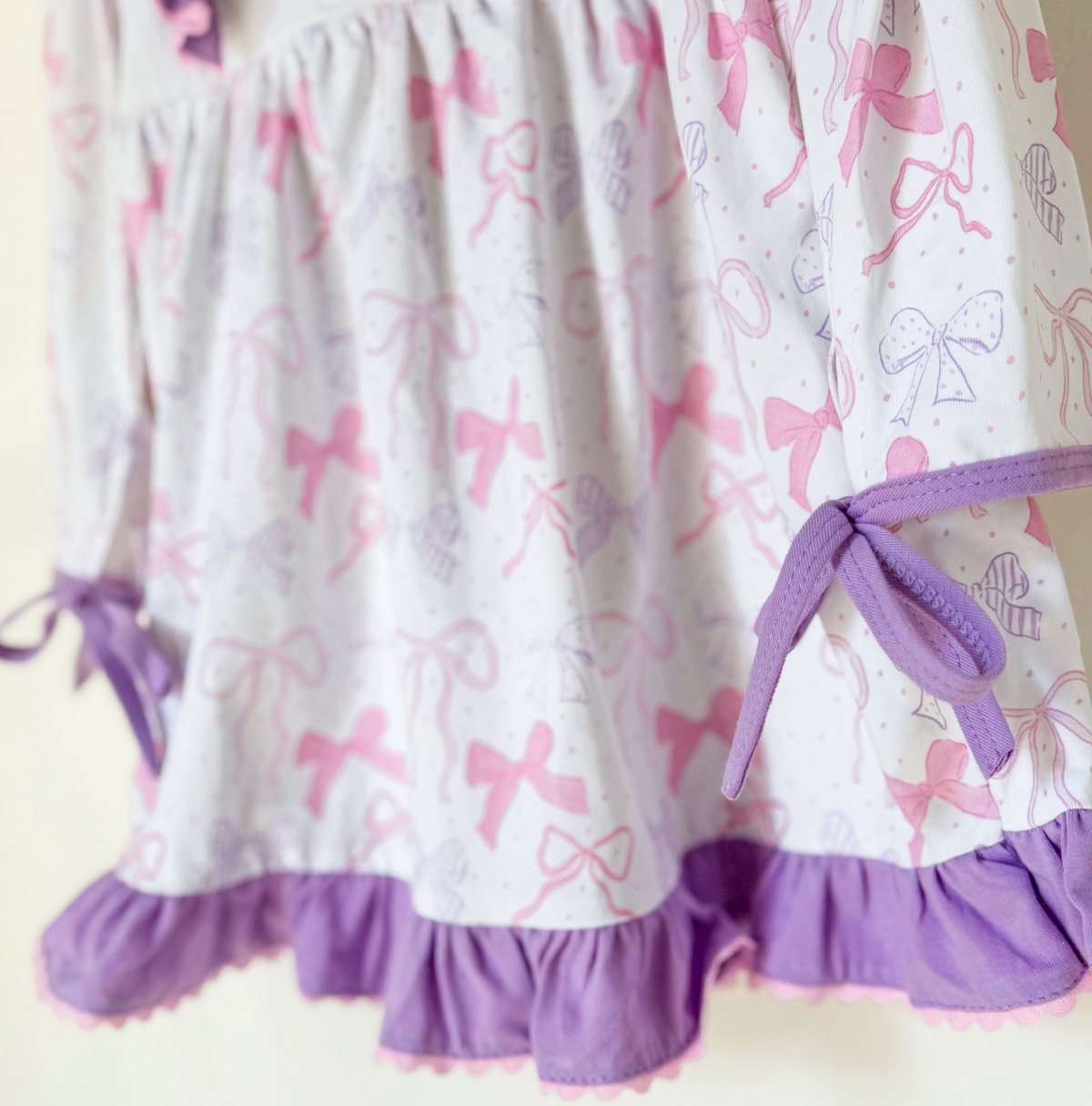 Detail of bow print fabric, ruffle hem, and side ribbon ties