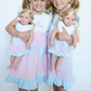 Girls holding dolls wearing matching dresses